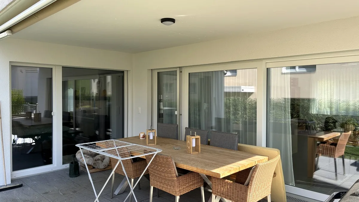 Gedeckter Sitzplatz mit Esstisch und direktem Wohnungszugang